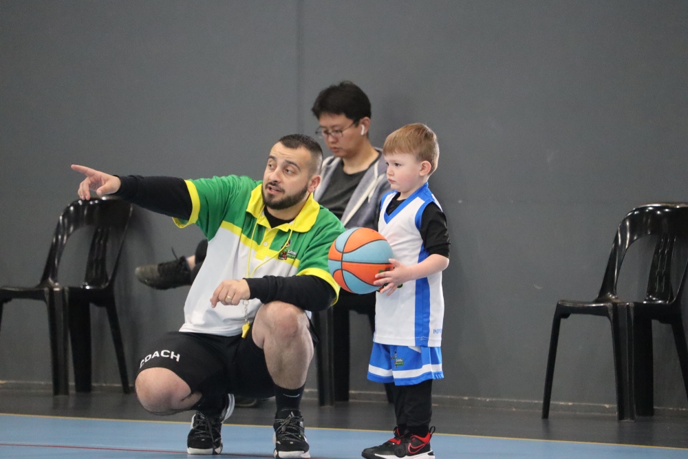 A man provides guidance to a young boy during a basketball game